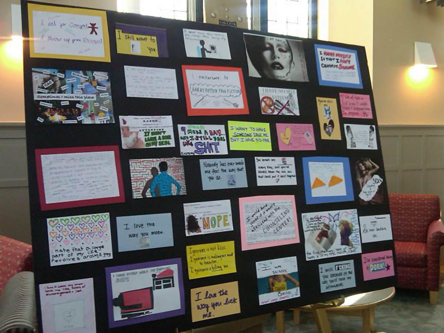 A black poster board, featuring an arrangement of post secrets, in many different shapes and colors, on display in Bryn Mawr’s campus center. 